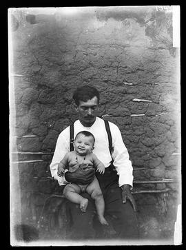 Fazendeiro do Tigre sentado com criança de 6 meses no colo.