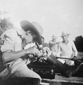 Gladstone Deane examinando lâminas ao microscópio em barco