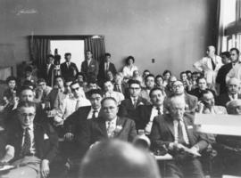 Plateia assistindo palestra não identificada durante evento sobre os 50 anos da descoberta da doe...