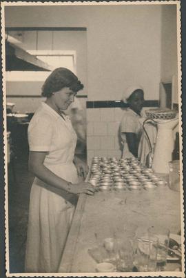 Cozinheira com formas de empadas na cozinha do sanatório Getúlio Vargas