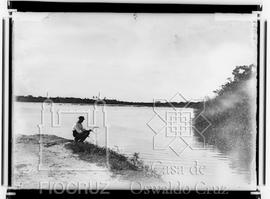 Homem em margem de rio segurando rede