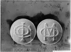 Medalhas com as iniciais do Instituto Oswaldo Cruz e outra com as iniciais OM