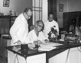 Antonio Viegas Pugas em sua mesa de desenho, observado por Herman Lent e Ademar Guilherme