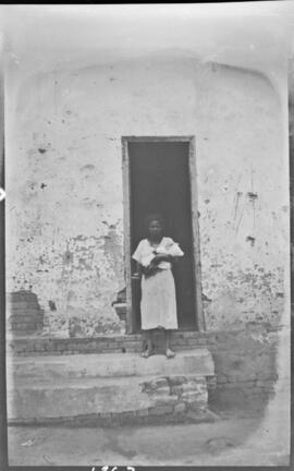 Mulher em frente à porta segurando um bebê - Estrada de Minas Gerais (MG)