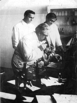 Oswaldo Cruz ao microscópio em laboratório de Manguinhos, observado por seu filho Bento Oswaldo C...